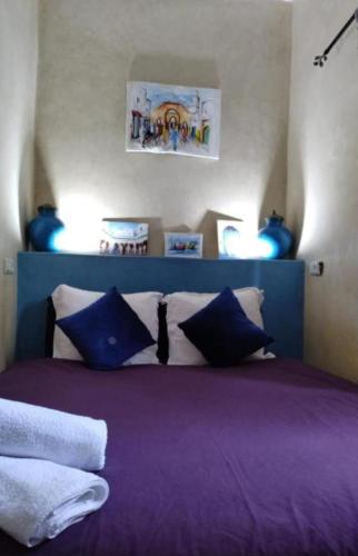 a bedroom with a purple bed with blue pillows at Dar safa in Essaouira