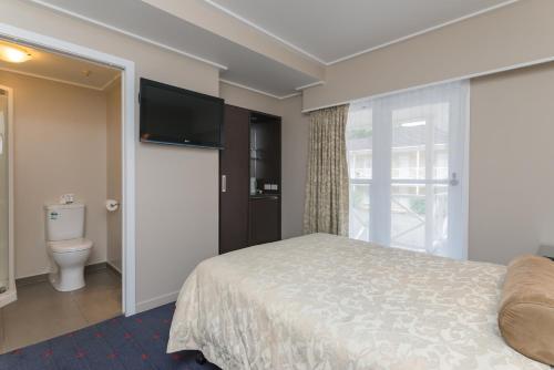 a hotel room with a bed and a toilet at Discovery Settlers Hotel in Whangarei