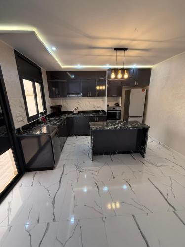 a kitchen with black cabinets and a marble floor at Villa piscine Saïdia 3 chambres in Saidia 