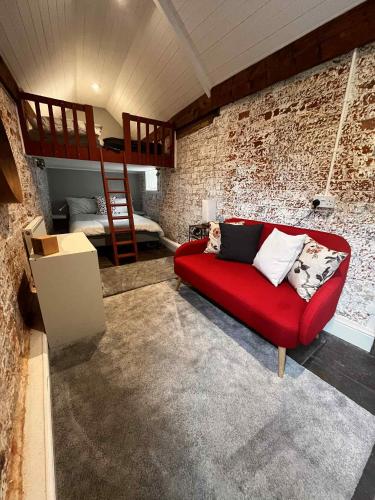 a living room with a red couch and a bunk bed at Charming Dorset Seaside Escape in Burton