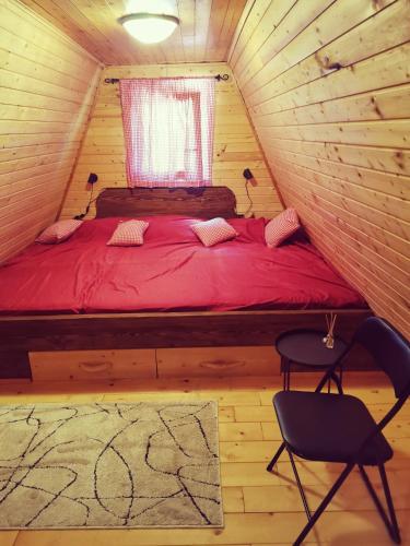 a bedroom with a red bed in a tree house at Planinska kuća BRDO in Zlobin