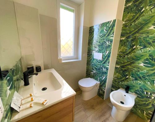 a bathroom with a sink and a toilet with a leaf wallpaper at LA RIVA DEL '44 Apartments - Elegant, spacious, and bright holiday homes just a few steps from Nettuno's finest beach in Nettuno
