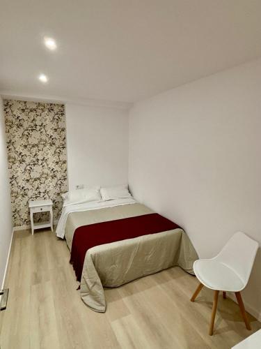 a bedroom with a bed and a white chair at Apartamentos do porto Malpica in Malpica