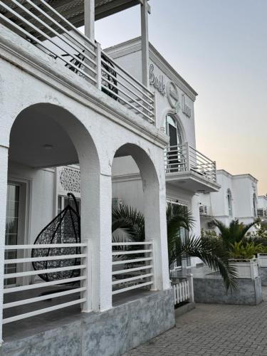 a white building with a balcony and a store at Book Inn in Astara