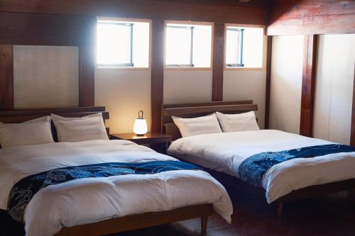 two beds in a room with two windows at 泊まれる文化交流施設 盆宿U bon-yadoU in Nishimonai