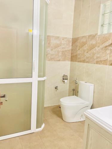 a bathroom with a white toilet and a shower at Olu Vila Private Cabana in Mabodale
