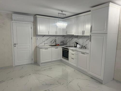 eine weiße Küche mit weißen Schränken und einer Spüle in der Unterkunft GRAND RESORT APARTAMENTS DARIS -free parking in Kasanlak