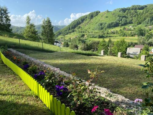 a green fence with flowers in a field at Hilltop cabin in Podgorica