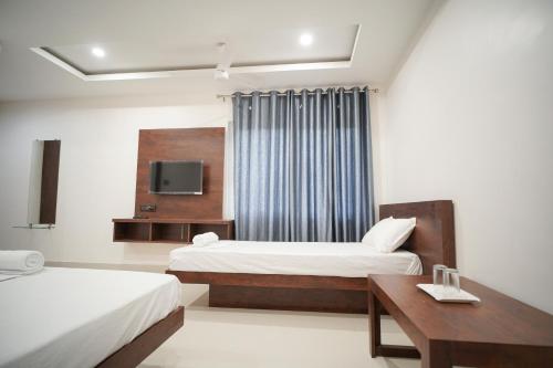 Royal Majestic Lodge في غاواهاتي: غرفة فندقية بسريرين وتلفزيون