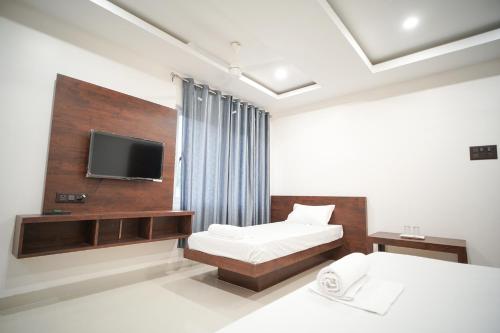 Royal Majestic Lodge في غاواهاتي: غرفة فندق بها سريران وتلفزيون بشاشة مسطحة