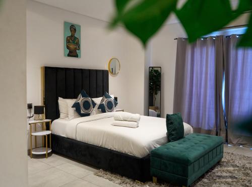 a bedroom with a large bed and a green chair at RoyalRest at Signature CPG in Accra