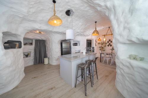 a kitchen and living room with a bar with stools at Complejo Cuevas Otto in Baza