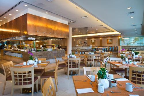 a restaurant with wooden tables and chairs and a bar at Agamim by Isrotel Collection in Eilat