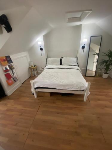 a bedroom with a bed with white sheets and a wooden floor at 1 bedroom house, Seven Sisters, Tottenham in London