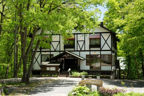 a black and white house in the middle of trees at Hakuba Skala Inn in Hakuba