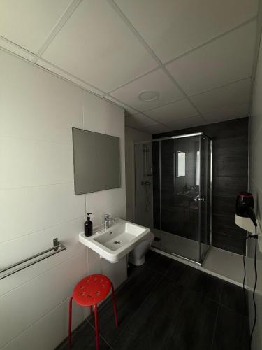 a bathroom with a sink and a red stool at Hostal B and B Benidorm in Benidorm