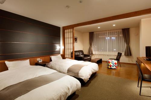 函館市にある湯の川温泉 笑 函館屋のベッド2台とデスクが備わるホテルルームです。
