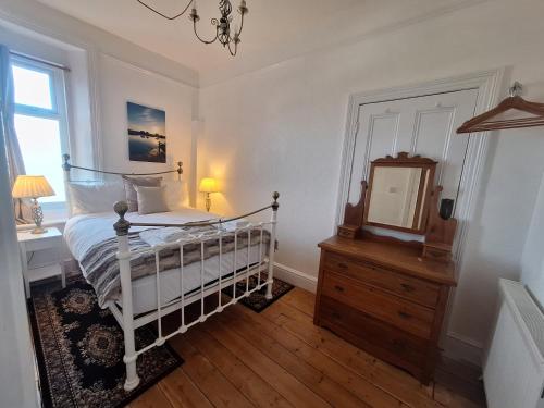 a bedroom with a bed and a mirror and a dresser at Kenmuire Apartment in Weymouth