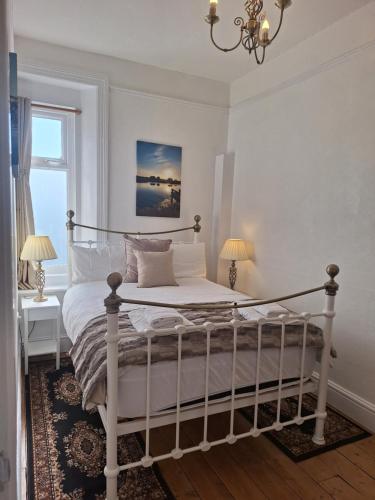 a bedroom with a white bed with a chandelier at Kenmuire Apartment in Weymouth
