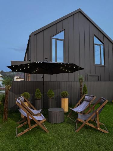two chairs and an umbrella in front of a house at Weekend house in Verkhovyna