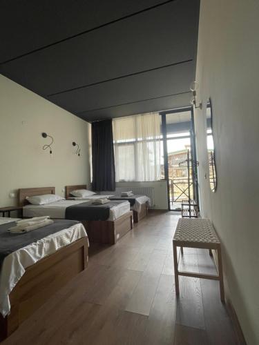 Pokój z 3 łóżkami i ławką w nim w obiekcie Hotel Echoes w mieście Stepancminda