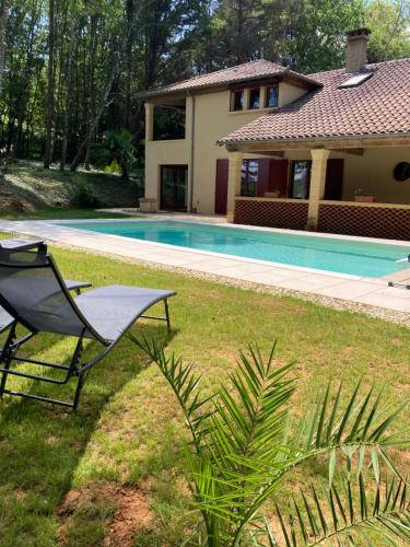une cour avec une chaise, une maison et une piscine dans l'établissement Gîte LES BAMBOUS, à Manaurie