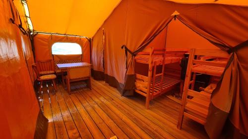 une tente orange avec un lit et des chaises à l'intérieur dans l'établissement Tente lodge la perche, à Le Lonzac