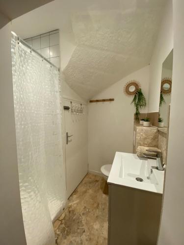 une salle de bain blanche avec une douche et un lavabo dans l'établissement Appartement au cœur du village, à Saint-Rome-de-Tarn