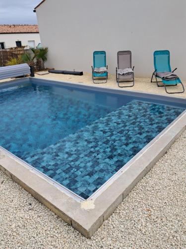 une piscine avec deux chaises et une piscine dans l'établissement Appartement Soubise, le Bonheur Côté Mer, à Soubise