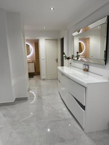 une salle de bain blanche avec un lavabo et un miroir dans l'établissement Le Prestigieux - plage, à Antibes