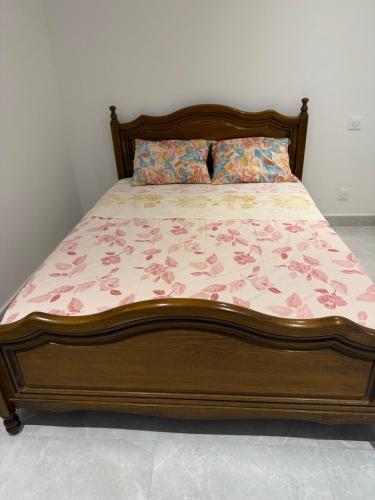 - un lit avec un cadre en bois et un couvre-lit floral dans l'établissement Le Prestigieux - plage, à Antibes