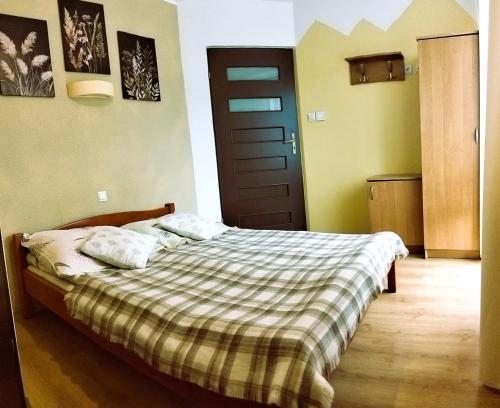 a bedroom with a bed with a plaid blanket and a door at Zielone Zacisze in Krościenko