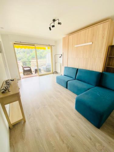 un salon avec un canapé bleu et une table dans l'établissement Le Patricia studio balcon calme vue clim, à Menton