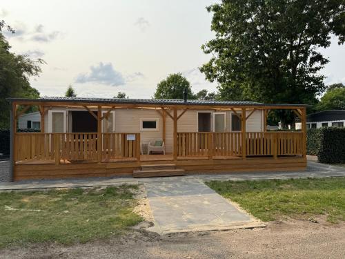 a mobile home with a porch and a deck at Luxe chalet op 5-sterren camping met comfortabel ingerichte veranda - parkkosten zijn inbegrepen in Sevenum