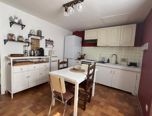une cuisine avec des armoires blanches et une table et des chaises dans l'établissement La Maison Aurélia, à Riez