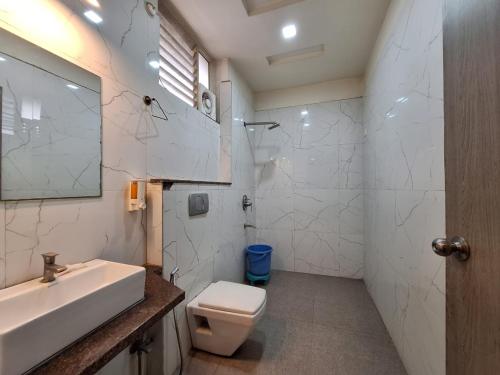 a white bathroom with a sink and a toilet at Hotel Mayur Palace in Bhopal