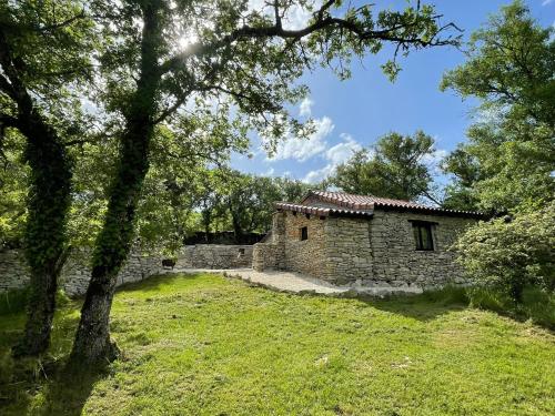 an old stone building in a field with trees at Mas de Méjas Gîte La Casaline in Calvignac