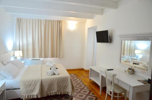 Una habitación de hotel con una cama, un escritorio y un espejo. en L'araucaria Le Camere, en Riola Sardo