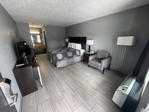 a hotel room with a bed and a chair at Budget Inn Sanford International Airport in Sanford
