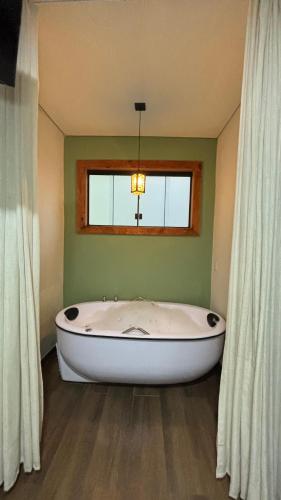 a large white tub in a room with a window at Hotel Chão Mineiro in São Thomé das Letras