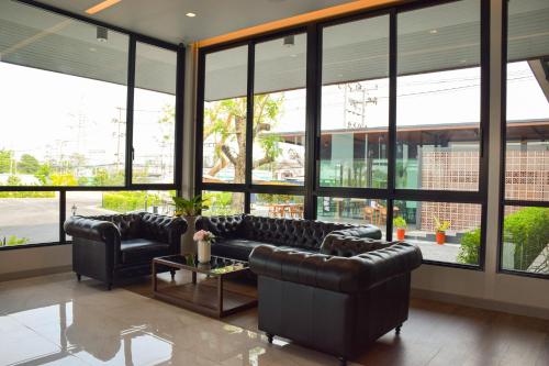 a living room with leather furniture and large windows at The Horizon Groove Hotel in Ban Khlong