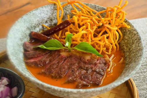 a bowl of food with meat and noodles at The Horizon Groove Hotel in Ban Khlong