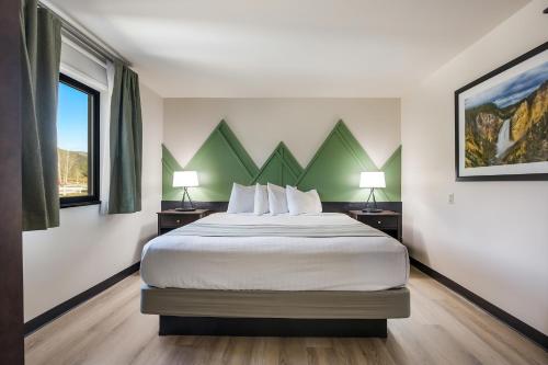a hotel room with a bed and two windows at Mountain Vista Hotel in West Yellowstone