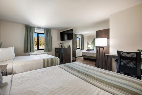 a hotel room with two beds and a desk at Mountain Vista Hotel in West Yellowstone