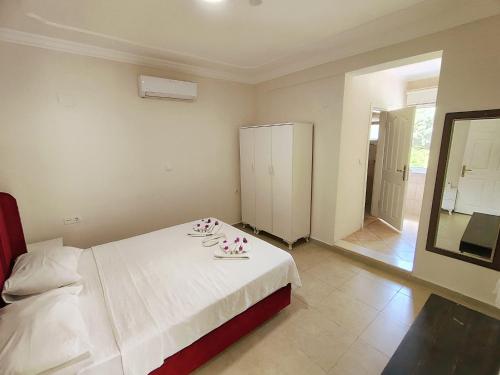 a bedroom with a white bed and a mirror at Bucak Apart Hotel Göcek & Beach in Göcek