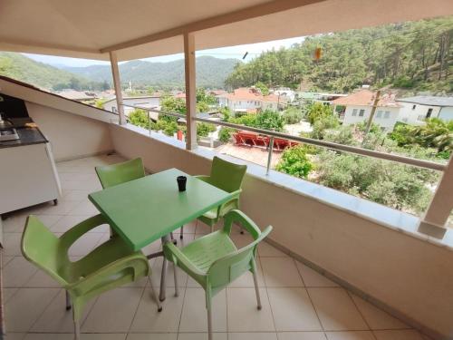 a green table and chairs on a balcony with a view at Bucak Apart Hotel Göcek & Beach in Göcek