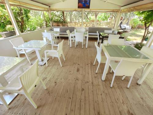 a patio with white tables and chairs and a table and chairs at Bucak Apart Hotel Göcek & Beach in Göcek