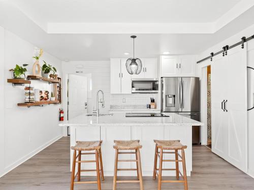 a kitchen with white cabinets and bar stools at Anastasia Island Villa Upper Level plus Rooftop in Saint Augustine