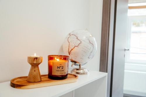 a candle and a globe on a white shelf at Duplex spacieux centre-ville de Spa in Spa