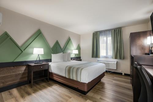 a hotel room with a bed with green and white walls at Mountain Vista Hotel in West Yellowstone